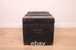 A vintage black wooden trunk with hinged lid blanket box log storage