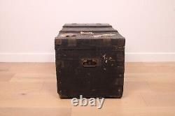 A vintage black wooden trunk with hinged lid blanket box log storage