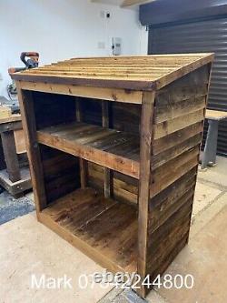 Abri à bûches rustique en bois avec étagère pour petit bois.