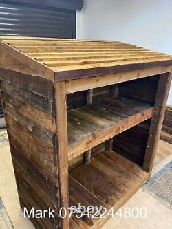 Abri à bûches rustique en bois avec étagère pour petit bois.